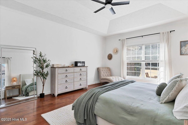 bedroom featuring baseboards, a raised ceiling, wood finished floors, and a ceiling fan