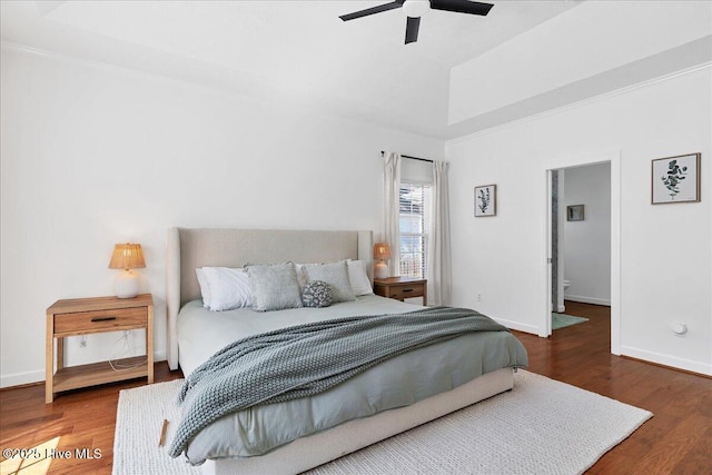 bedroom featuring a ceiling fan, a raised ceiling, baseboards, and wood finished floors