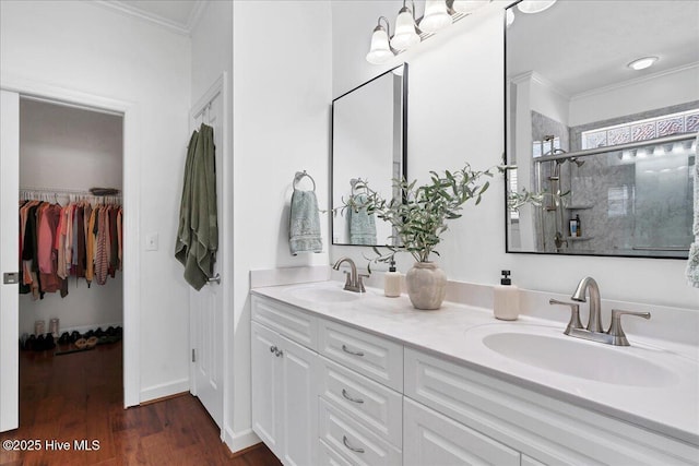 bathroom featuring a sink, wood finished floors, a stall shower, and crown molding