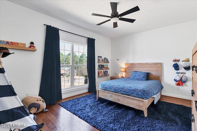 bedroom featuring a ceiling fan, wood finished floors, baseboards, and a textured ceiling