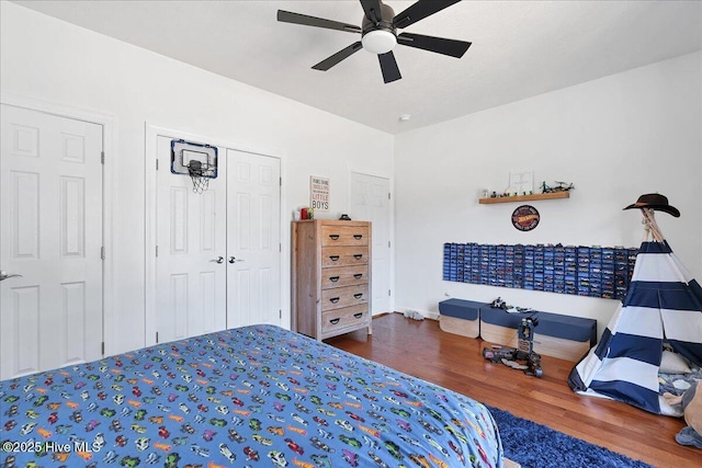 bedroom with baseboards, wood finished floors, a closet, and ceiling fan