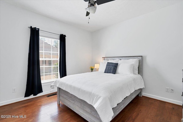 bedroom featuring ceiling fan, visible vents, baseboards, and wood finished floors