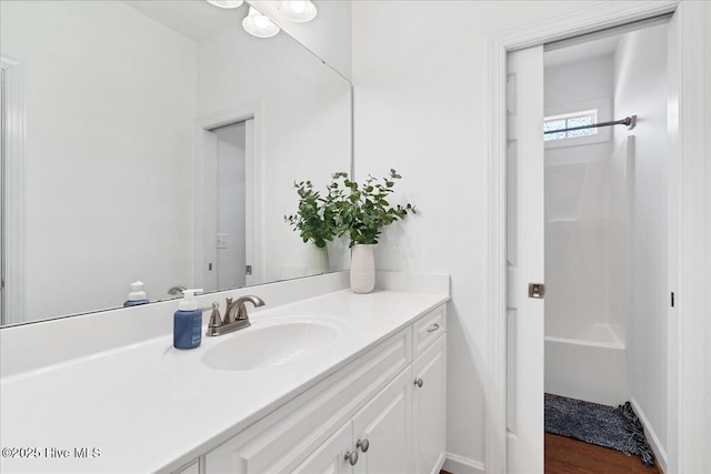 full bath with baseboards, vanity,  shower combination, and wood finished floors