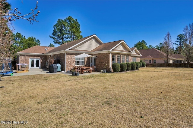 back of property featuring a patio area, a yard, french doors, and brick siding