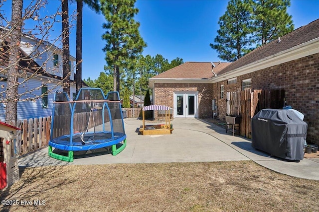 view of patio featuring french doors, a trampoline, grilling area, and fence