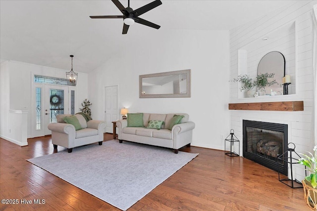 living room with high vaulted ceiling, a ceiling fan, wood finished floors, a large fireplace, and baseboards