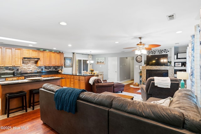 living room with visible vents, a ceiling fan, wood finished floors, a fireplace, and recessed lighting