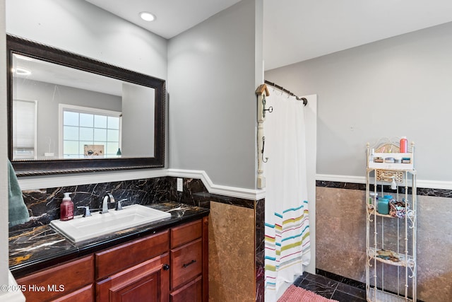 bathroom with a wainscoted wall, curtained shower, tile walls, and vanity