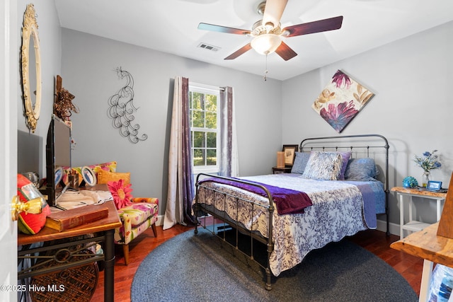 bedroom featuring baseboards, ceiling fan, visible vents, and wood finished floors