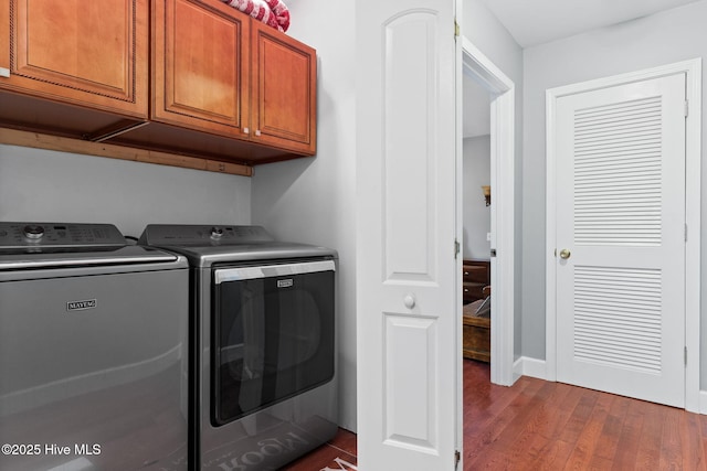 washroom with cabinet space, washer and clothes dryer, and dark wood-style flooring