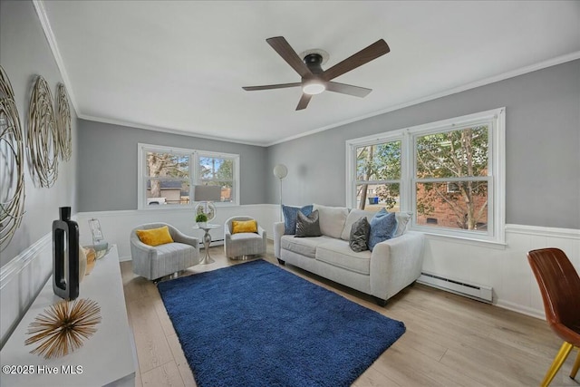 living area with a wainscoted wall, a baseboard radiator, wood finished floors, and crown molding