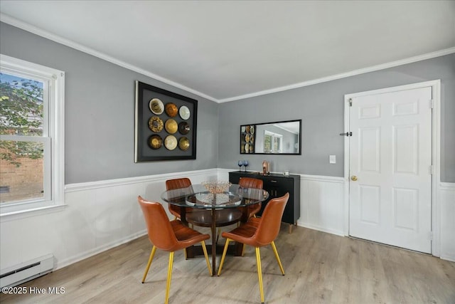 dining space featuring a baseboard radiator, ornamental molding, light wood-style flooring, and wainscoting