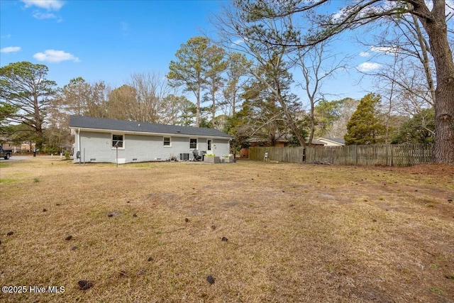 back of property with crawl space, cooling unit, fence, and a lawn