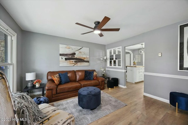 living room with light wood-type flooring, ceiling fan, and baseboards