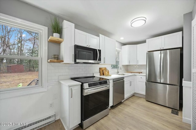 kitchen featuring open shelves, stainless steel appliances, a baseboard radiator, white cabinets, and a sink