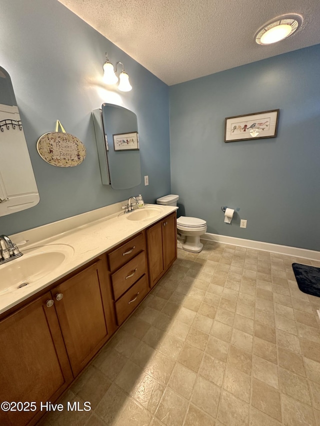 bathroom with baseboards, a sink, a textured ceiling, and toilet