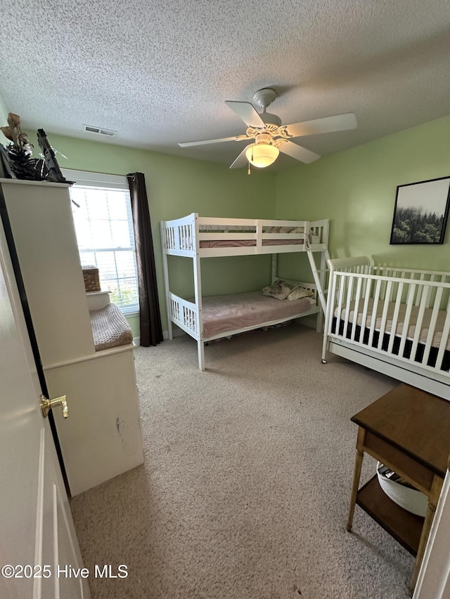 bedroom with visible vents, ceiling fan, and a textured ceiling