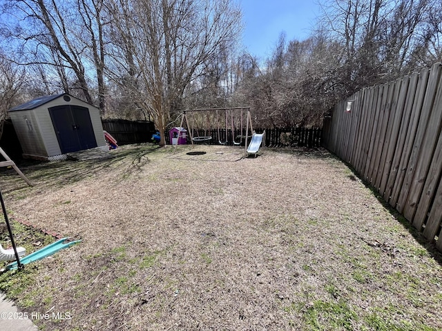 view of yard with a fenced backyard, a storage unit, a playground, and an outdoor structure