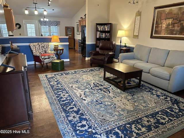 living room with vaulted ceiling, dark wood-style floors, and a notable chandelier