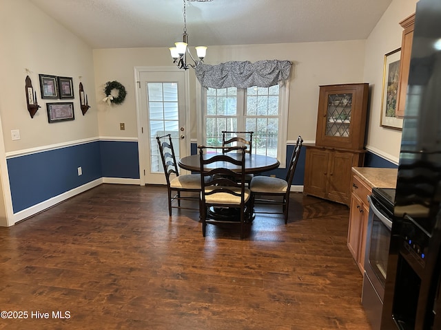 dining area featuring a notable chandelier, vaulted ceiling, and dark wood-type flooring