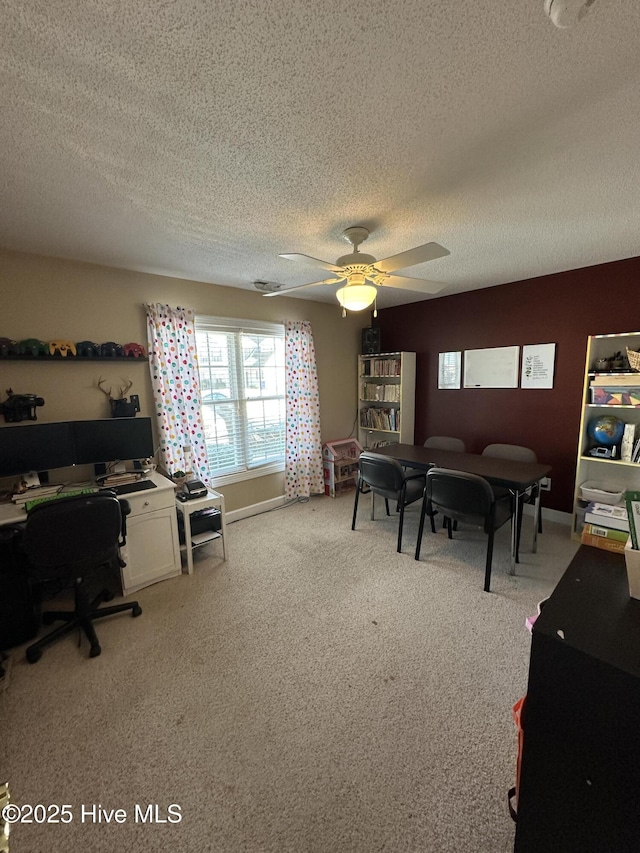 home office with light carpet, a textured ceiling, baseboards, and a ceiling fan