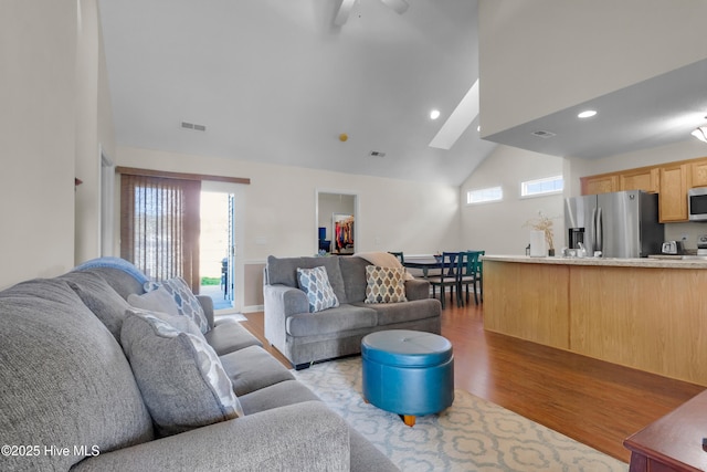 living room featuring high vaulted ceiling, recessed lighting, visible vents, and wood finished floors