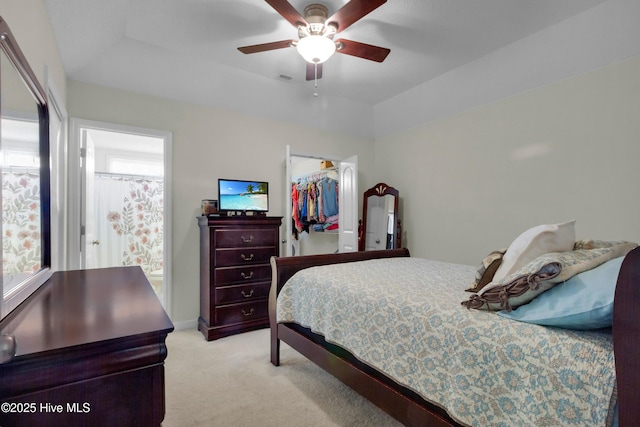 bedroom featuring light carpet, a ceiling fan, a spacious closet, a closet, and a tray ceiling