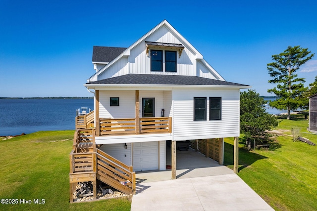 view of front of property featuring a front yard, driveway, roof with shingles, a water view, and board and batten siding