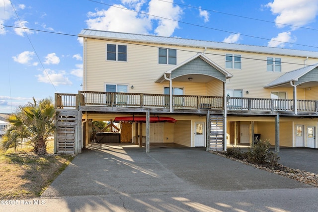 view of front of property featuring aphalt driveway, metal roof, a deck, a carport, and stairs