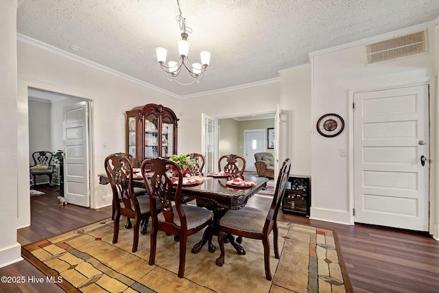 dining space featuring a notable chandelier, visible vents, ornamental molding, a textured ceiling, and wood finished floors