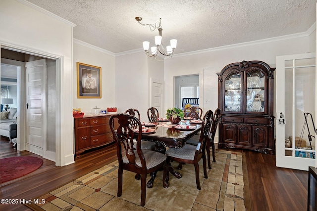 dining space with dark wood-type flooring, crown molding, a textured ceiling, and an inviting chandelier