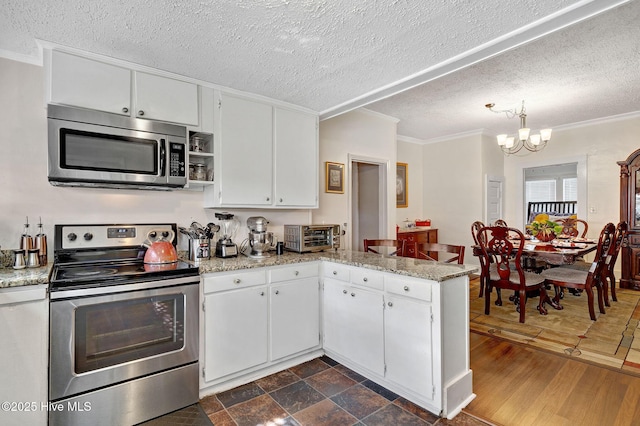 kitchen with a notable chandelier, a peninsula, appliances with stainless steel finishes, and white cabinets