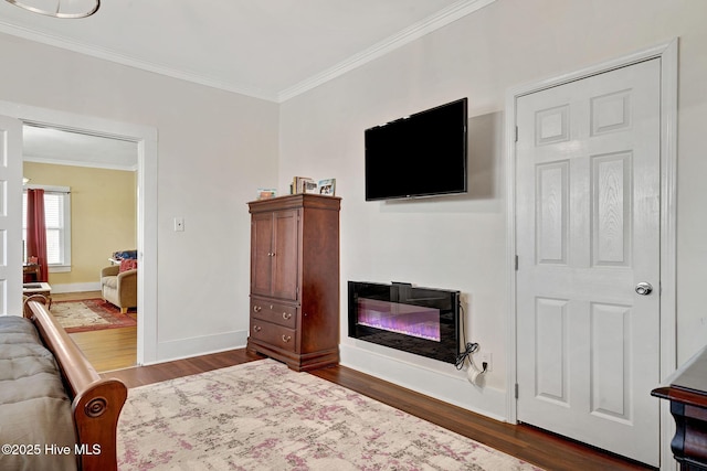 bedroom featuring baseboards, dark wood-style flooring, a glass covered fireplace, and crown molding