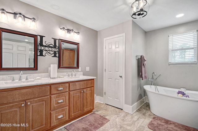 bathroom featuring a freestanding bath, double vanity, a sink, and baseboards