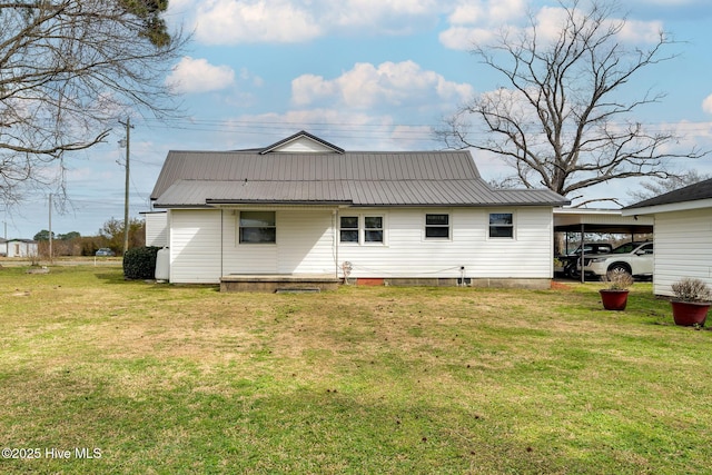 rear view of property with a carport, metal roof, and a lawn