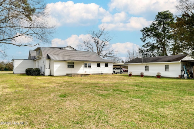 back of property with a lawn, metal roof, and a carport