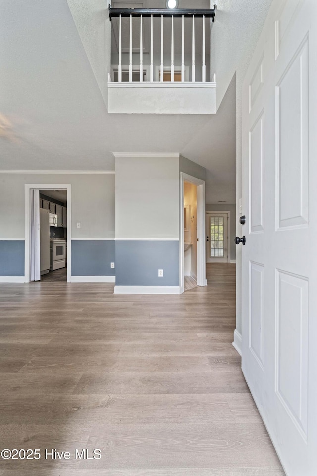 unfurnished living room with a high ceiling, baseboards, and wood finished floors