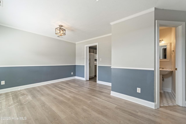 spare room with crown molding, wood finished floors, and baseboards