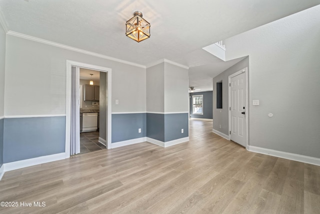 spare room featuring ornamental molding, baseboards, light wood finished floors, and a ceiling fan