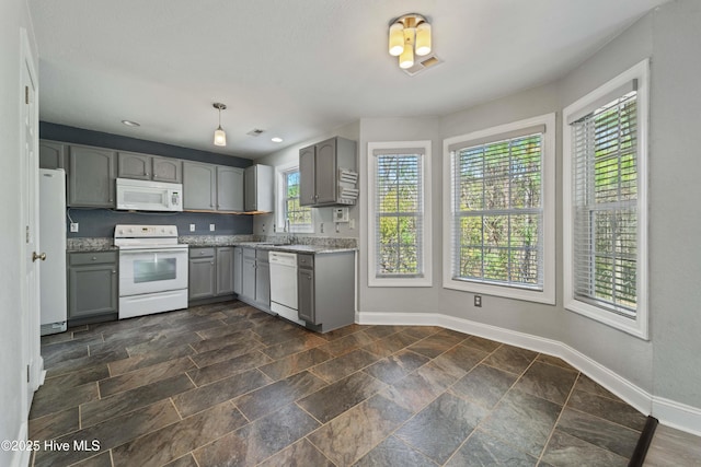 kitchen with gray cabinetry, white appliances, visible vents, baseboards, and stone finish floor