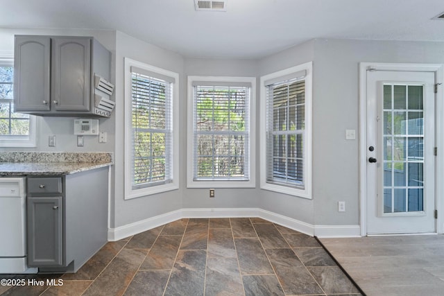 kitchen featuring baseboards, dishwasher, visible vents, and gray cabinetry