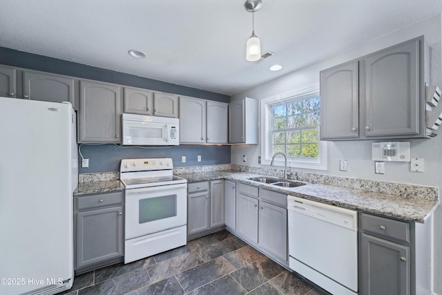 kitchen with light stone counters, pendant lighting, gray cabinets, a sink, and white appliances