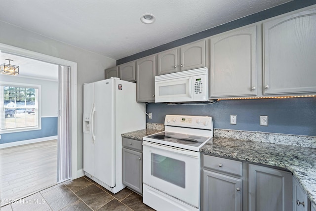 kitchen with white appliances, baseboards, gray cabinets, and dark stone countertops