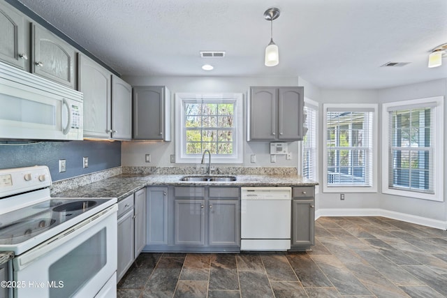 kitchen with gray cabinets, visible vents, a sink, white appliances, and baseboards