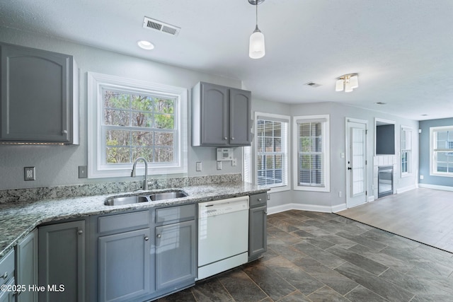 kitchen with light stone counters, gray cabinets, visible vents, white dishwasher, and a sink