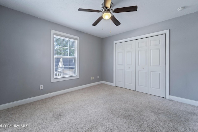 unfurnished bedroom featuring carpet floors, a ceiling fan, baseboards, and a closet