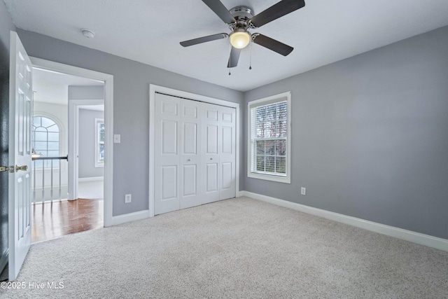 unfurnished bedroom featuring a closet, carpet, a ceiling fan, and baseboards