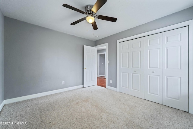 unfurnished bedroom with ceiling fan, a closet, baseboards, and carpet flooring