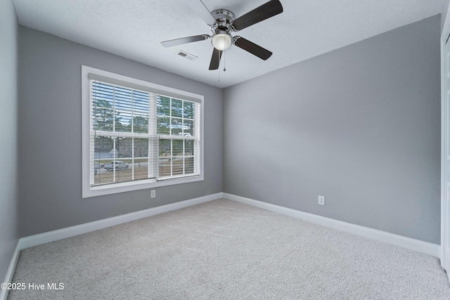 carpeted empty room featuring a ceiling fan, visible vents, a textured ceiling, and baseboards