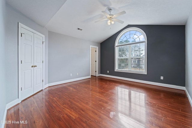 interior space with visible vents, a ceiling fan, vaulted ceiling, wood finished floors, and baseboards